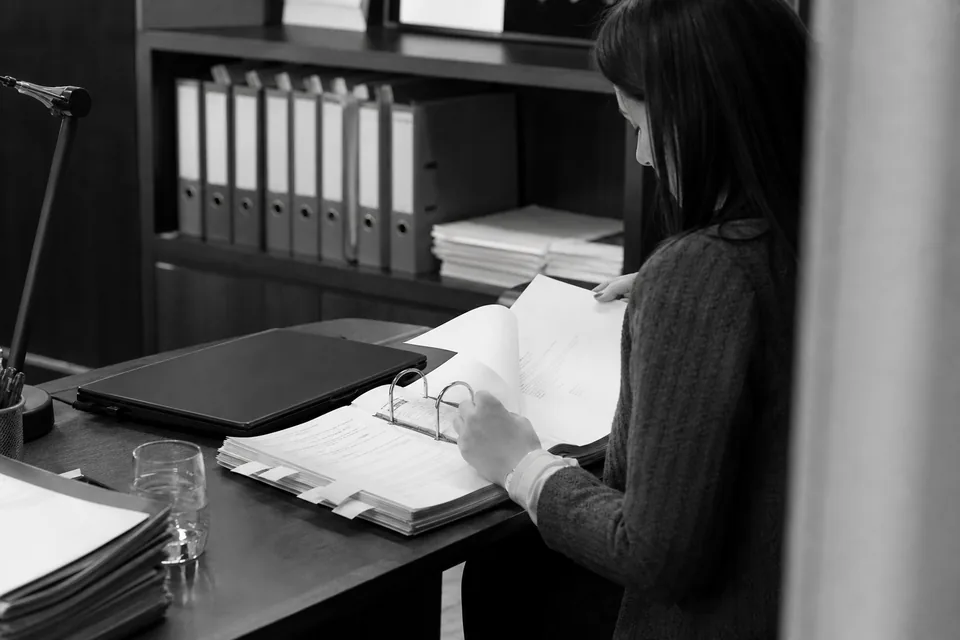 Segregator z kopiami pozwu i nakazu zapłaty na biurku obok laptopa